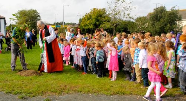 Archbishop Michael Jackson plants a tree with the help of caretaker, John Kelly, at the official opening and dedication of the extension at Carysfort NS on September 27. 