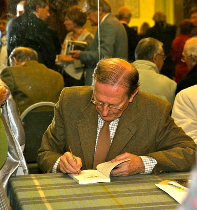 Retired clergyman, Patrick Semple, signs a copy of his new novel, Transient Beings, at its launch in the Knox Hall in Monkstown. 