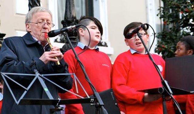 Paddy Moloney of the Chieftans plays at the Community Carol Singing outside the Mansion House on Saturday December 15 accompanying members of St Ultan’s School Choir. 