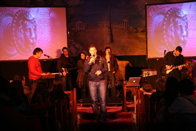 Greg Fromholz, Director of 3 Rock Youth speaking at Essential at Easter in Christ Church, Bray. In the background is the band Emmaus.