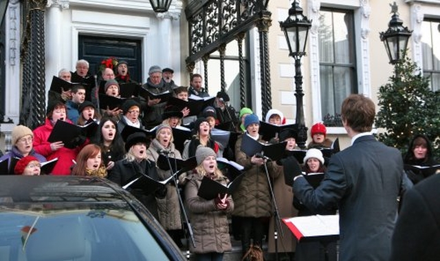 Ruaidhrí Ó Dálaigh conducts Cantairí Avondale at the community carol singing outside the Mansion House in Dublin.