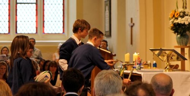 Students bring items representing school life to the altar during the service of dedication of Temple Carrig School. 