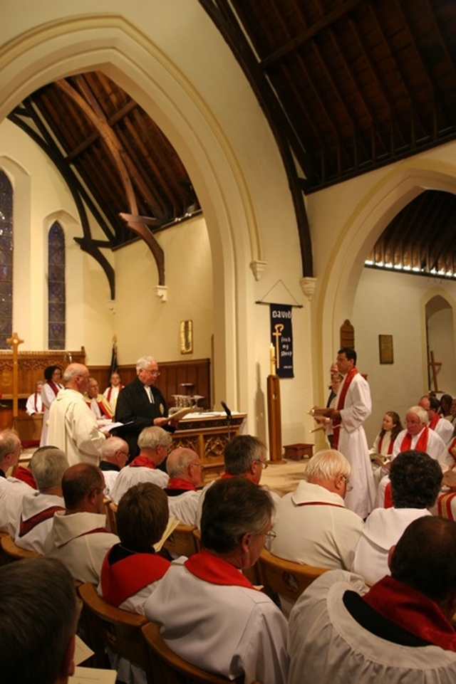 The Registrar, the Revd Canon Victor Stacey reads the Certificate of Nomination at the Institution of the Revd David Mungavin as Rector of Greystones (pictured standing right).