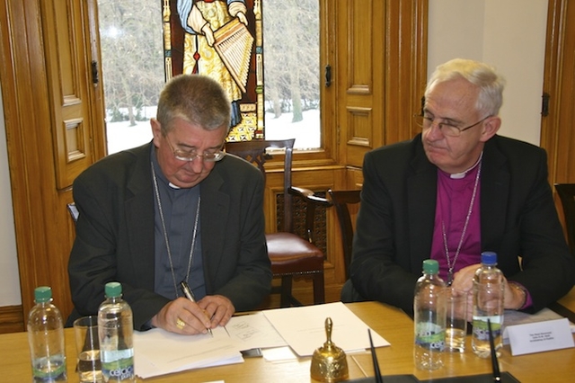 Roman Catholic Archbishop of Dublin Diarmuid Martin, who was voted Chairperson, signs the Constitution of the Dublin Inter Religious Council at their first meeting, as Church of Ireland Archbishop John Neill looks on. 