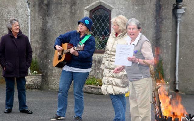 The leaders of the monthly children’s service at Inch Church Pat O’Malley (beside the fire) and Judy Deacom (with the guitar) get the first children’s Easter Vigil at the church underway. 