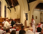 The Registrar, the Revd Canon Victor Stacey reads the Certificate of Nomination at the Institution of the Revd David Mungavin as Rector of Greystones (pictured standing right).