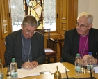 Roman Catholic Archbishop of Dublin Diarmuid Martin, who was voted Chairperson, signs the Constitution of the Dublin Inter Religious Council at their first meeting, as Church of Ireland Archbishop John Neill looks on. 