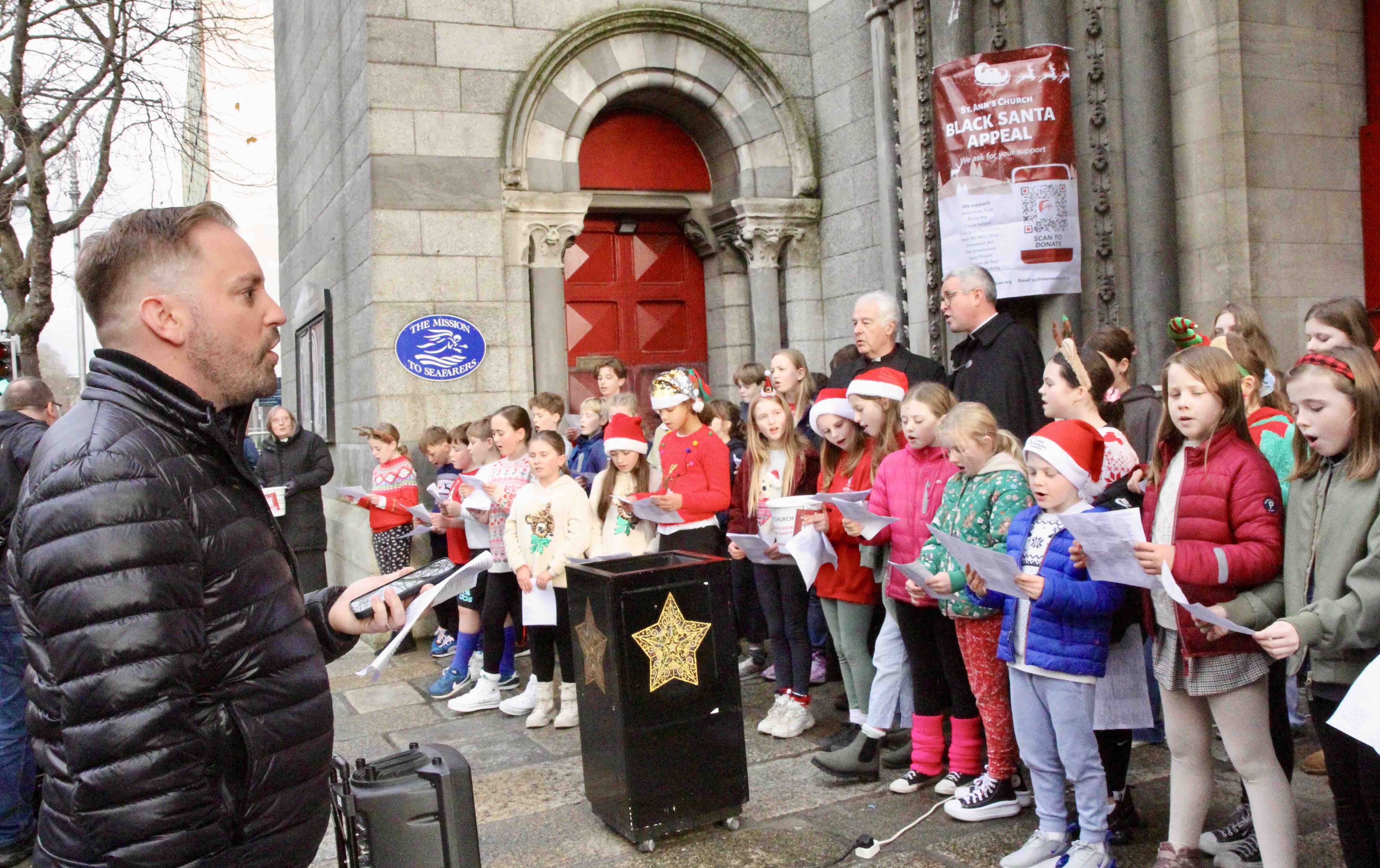 Ian Packham conducts the choir at the Black Santa launch at St Ann's.