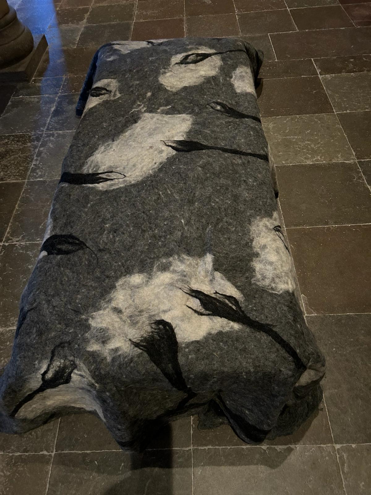 A bed made from felted wool in the crypt depicting looking up to see branches and clouds.
