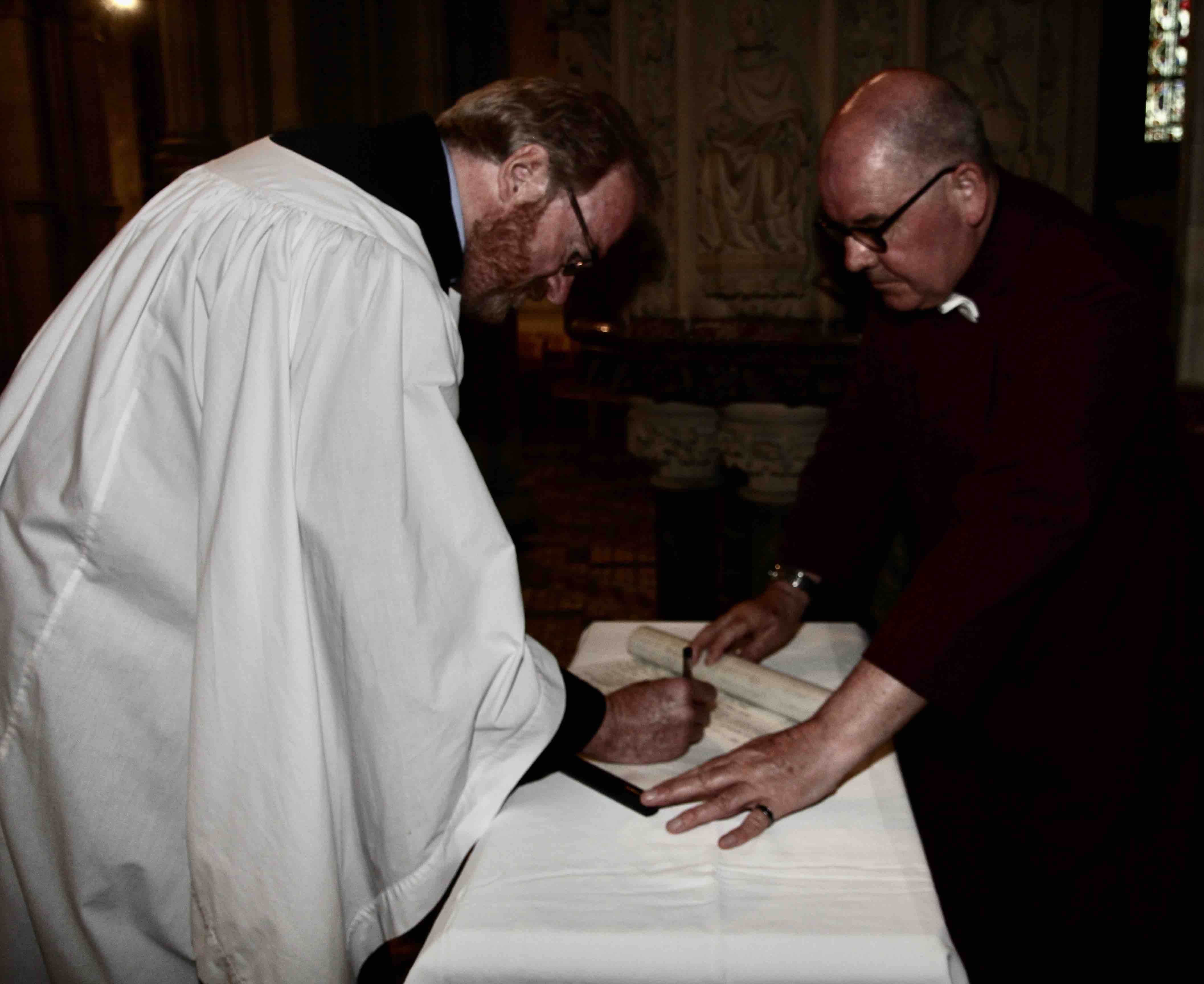 Canon Arthur Barrett signs the Chapter Role observed by Dean's Verger Fred Deane.