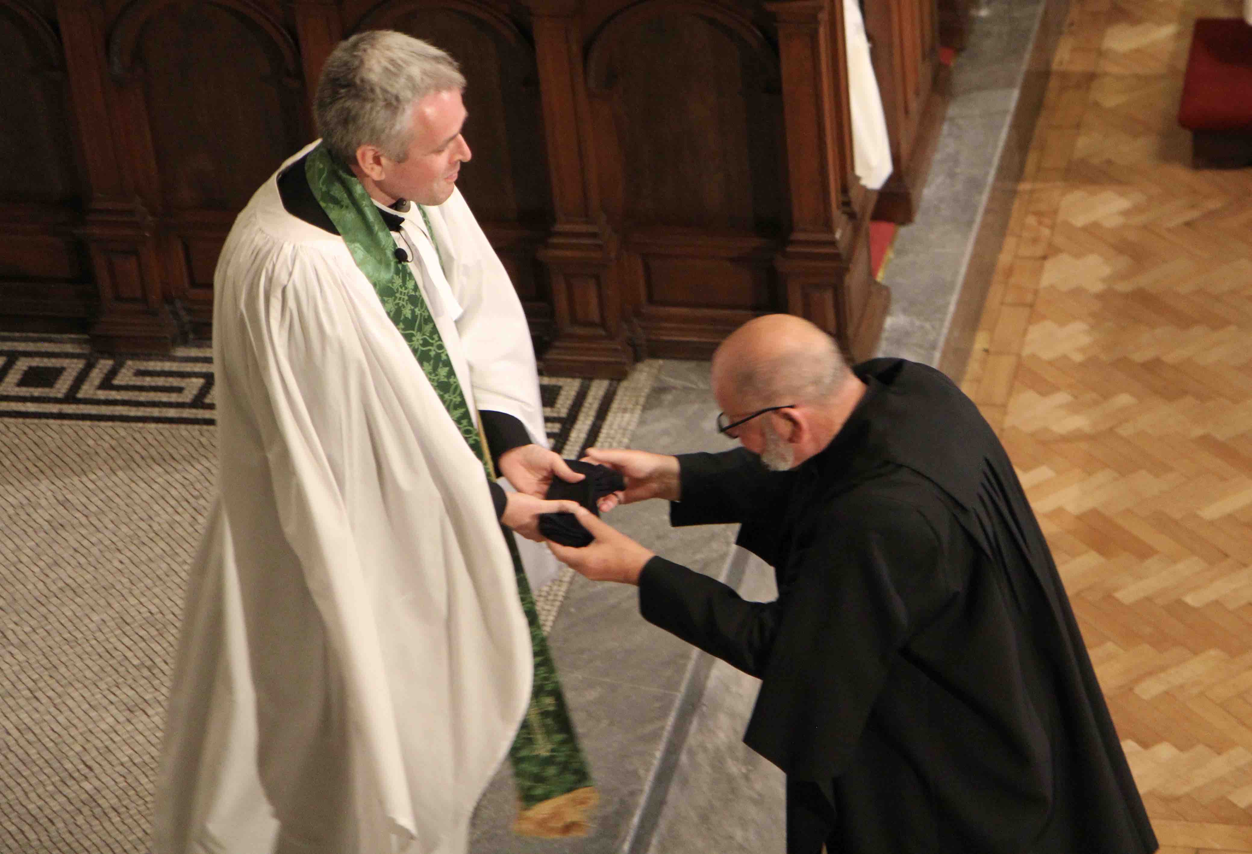 St Ann's caretaker Fred Deane presents the new Vicar of St Ann's with a pair of socks to keep him warm during the annual Black Santa Sit Out from the Dean of Belfast.