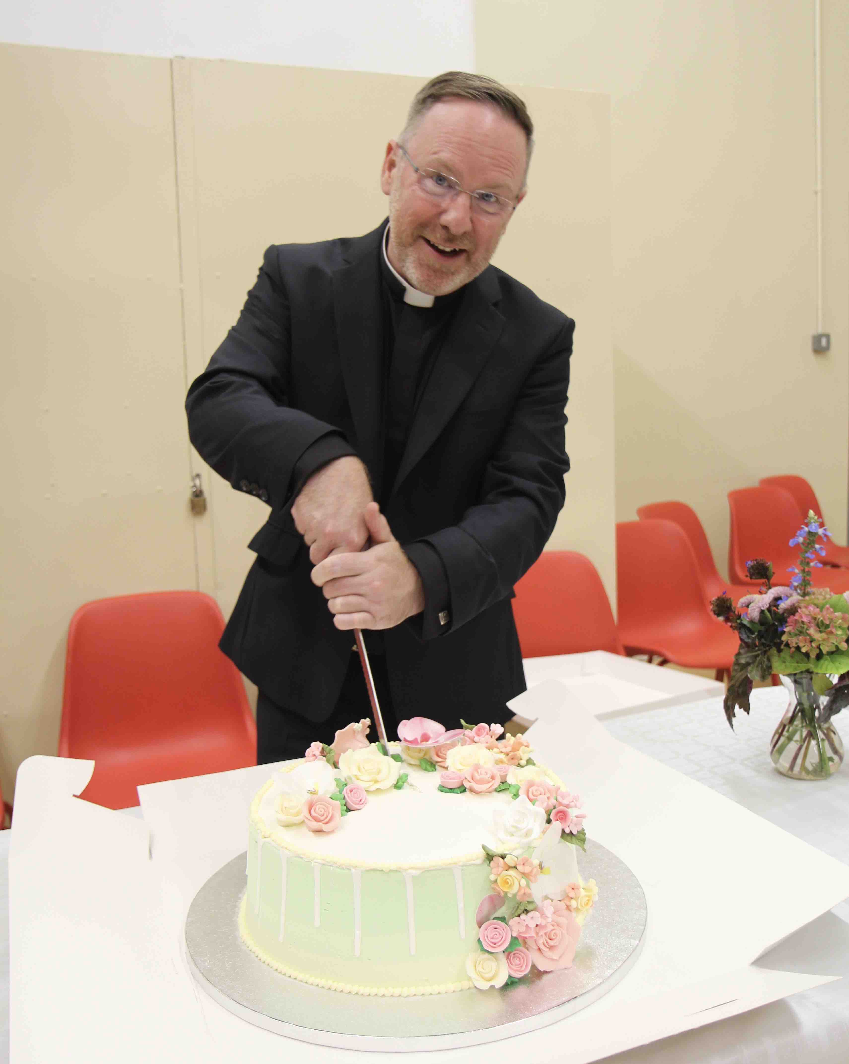 The Revd David White cuts a specially baked cake marking his institution as Rector of Zion